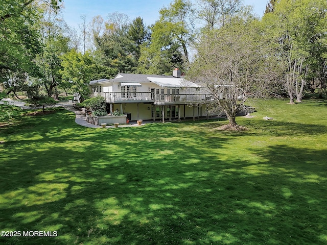 back of house featuring a yard, a wooden deck, and a chimney