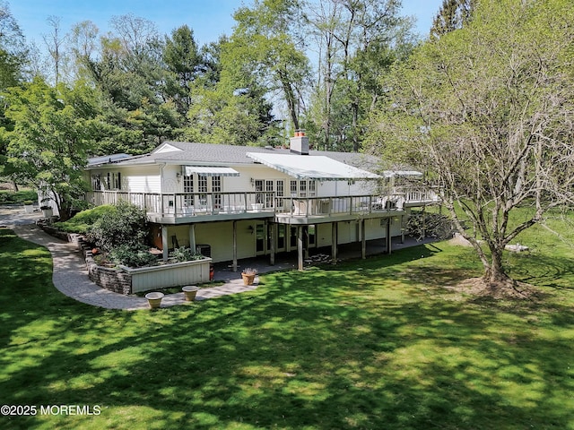 back of property with a yard, a deck, and a chimney