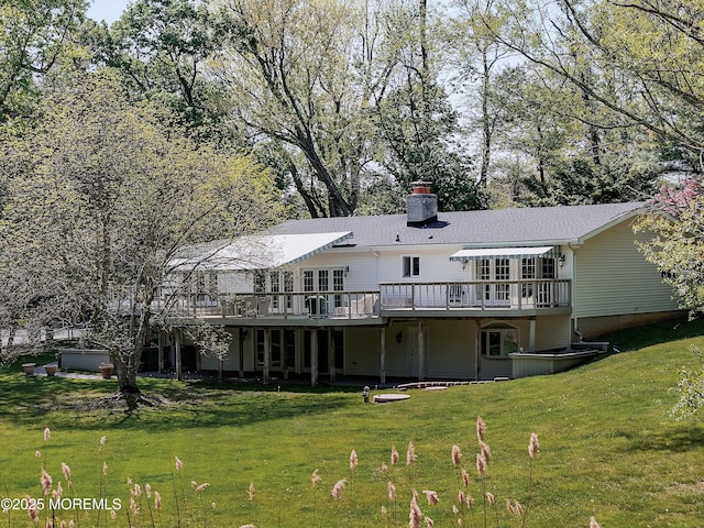 rear view of house with a lawn, a chimney, and a wooden deck