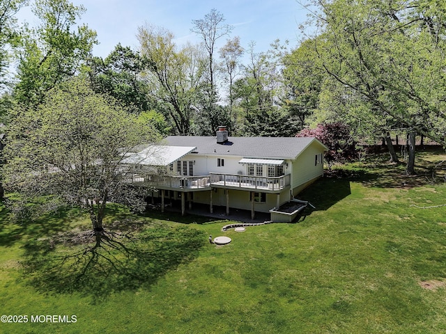 back of property with a yard, a chimney, and a wooden deck