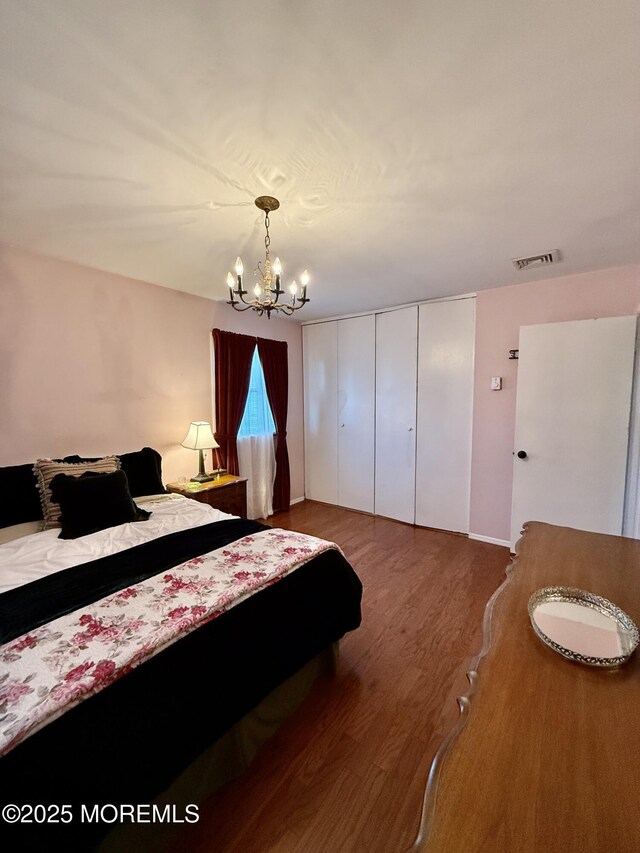 bedroom featuring a chandelier, wood finished floors, and a closet