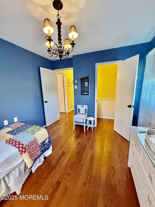 bedroom with a chandelier, wood finished floors, and heating unit