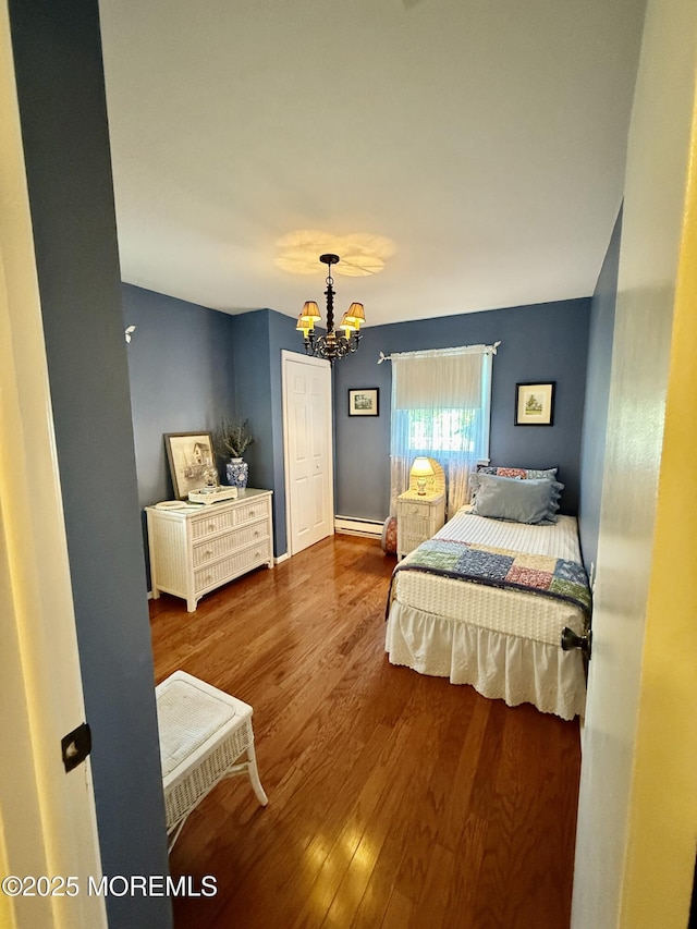 bedroom featuring a baseboard radiator, a chandelier, and wood finished floors