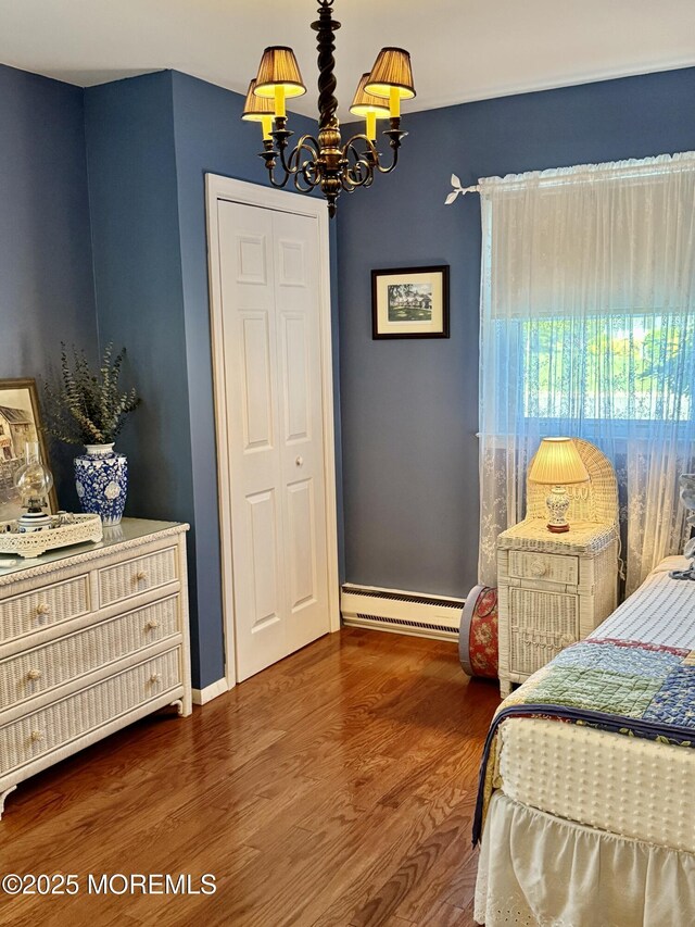 bedroom featuring baseboard heating, a chandelier, dark wood-style floors, and baseboards