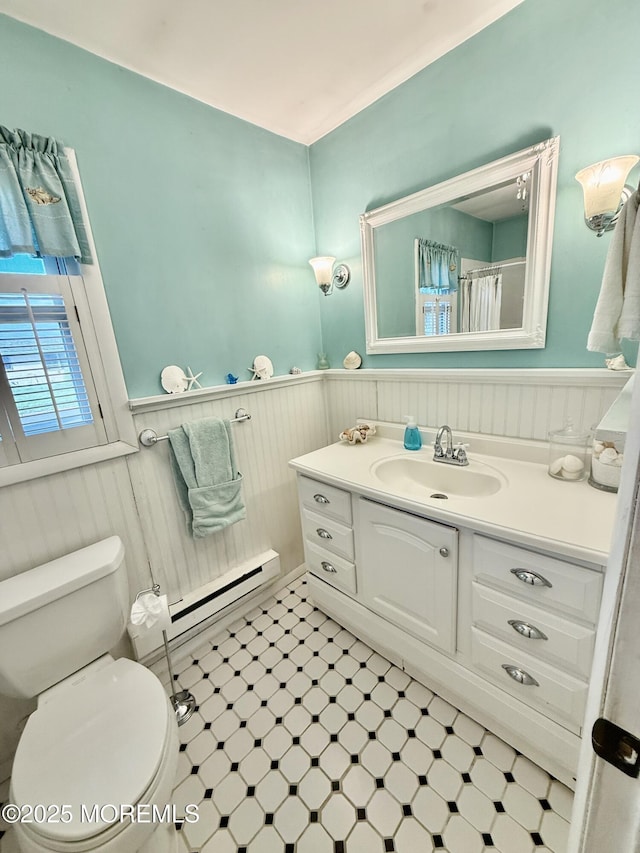 full bathroom featuring baseboard heating, a wainscoted wall, toilet, tile patterned floors, and vanity
