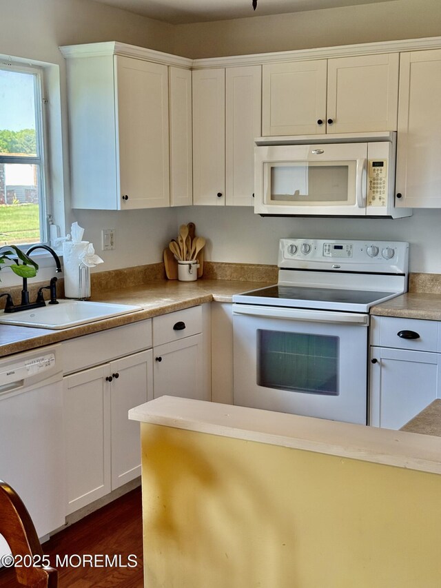 kitchen with white appliances, a sink, white cabinets, and light countertops