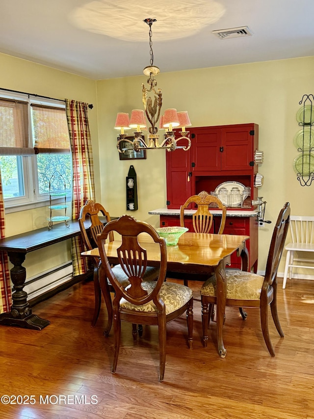 dining area featuring a chandelier, light wood-style flooring, and baseboard heating