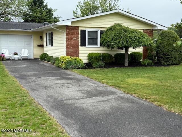 view of front facade with driveway, a garage, and a front yard