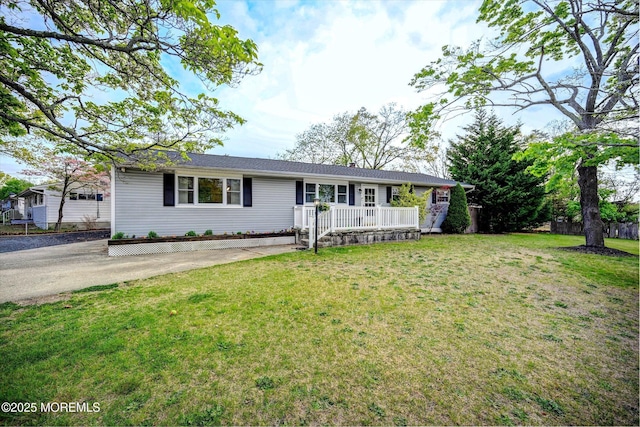 ranch-style house featuring covered porch and a front lawn