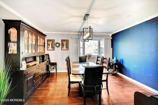 dining room with crown molding, baseboards, wallpapered walls, and dark wood finished floors