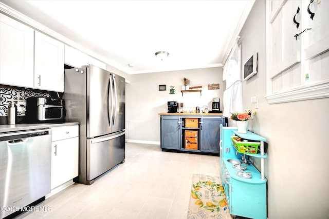 kitchen with stainless steel appliances, baseboards, white cabinetry, and ornamental molding
