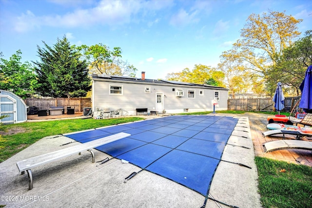 view of swimming pool with a shed, a fenced backyard, a fenced in pool, an outbuilding, and a patio area
