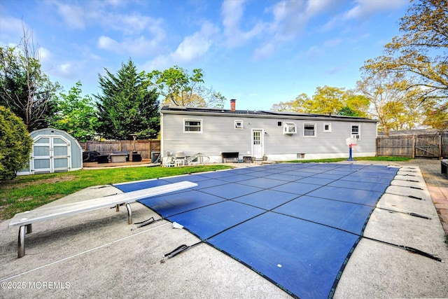 rear view of house with a fenced backyard, a shed, a fenced in pool, a patio area, and an outbuilding