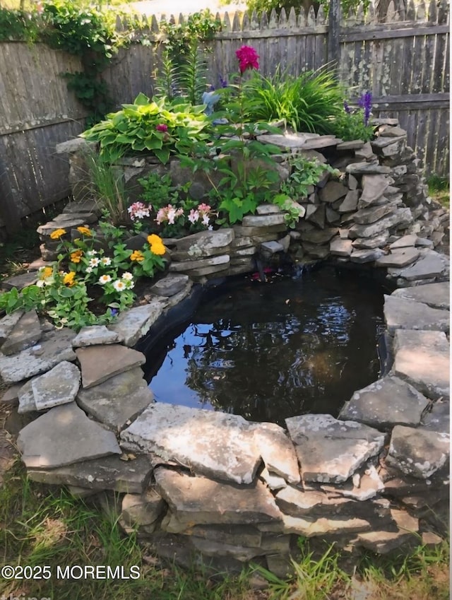 view of yard featuring a garden pond and fence