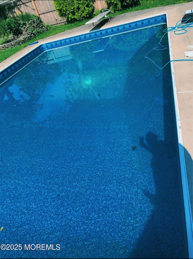 view of swimming pool featuring a diving board, a fenced in pool, and fence