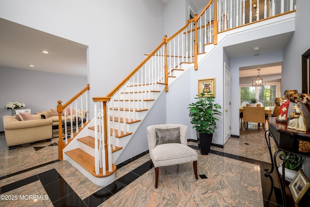 stairway with inlaid floor details, a high ceiling, recessed lighting, marble tiled flooring, and baseboards