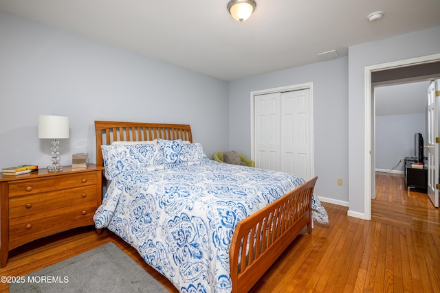 bedroom featuring wood-type flooring, a closet, and baseboards