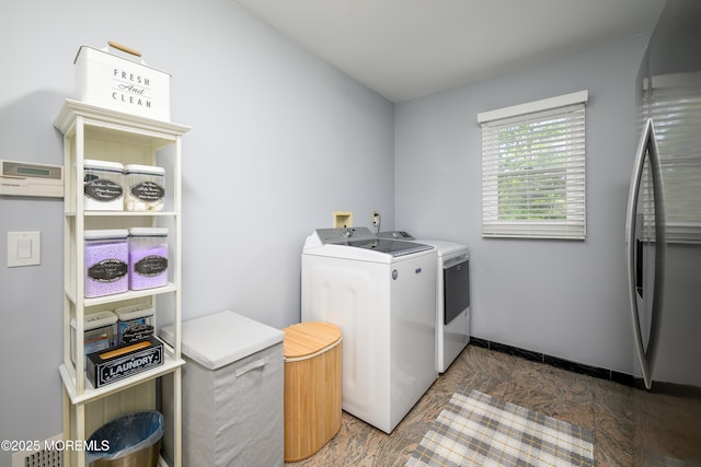 laundry room with washing machine and dryer, stone finish floors, and baseboards