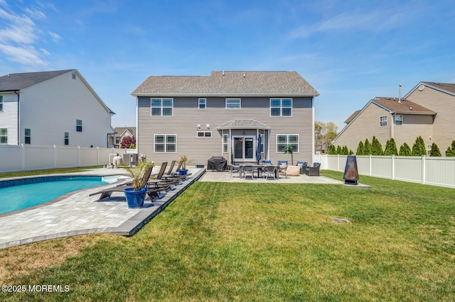 rear view of property featuring a fenced backyard, a fenced in pool, a lawn, and a patio area