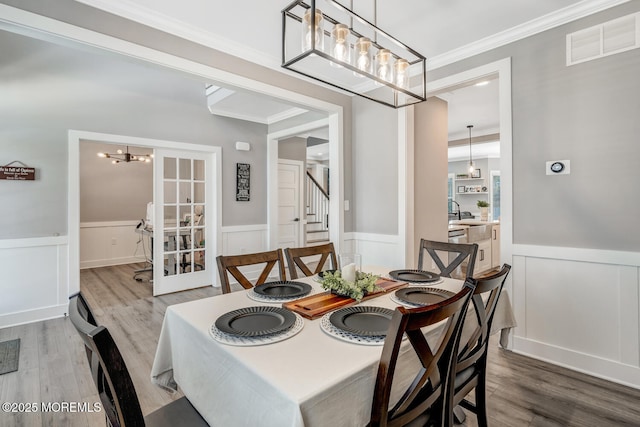 dining space featuring visible vents, wainscoting, an inviting chandelier, and wood finished floors