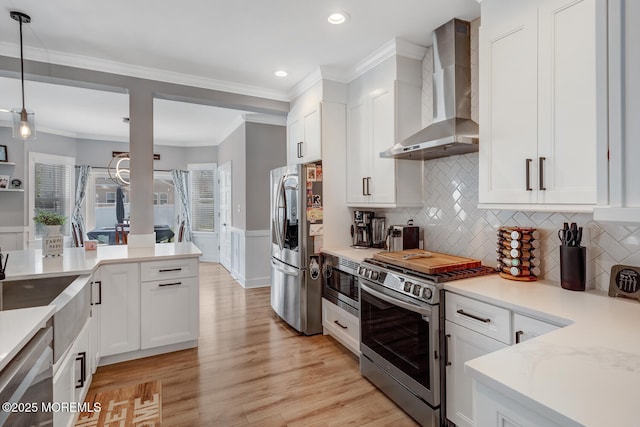 kitchen with wall chimney range hood, stainless steel appliances, white cabinets, and recessed lighting
