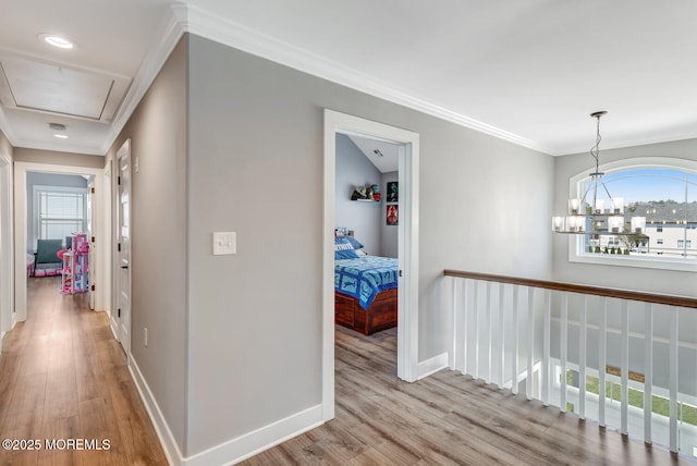 hall with crown molding, baseboards, attic access, and wood finished floors