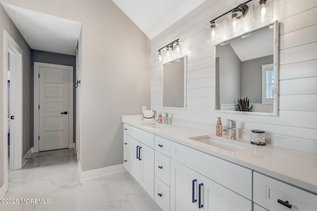 full bathroom featuring baseboards, a sink, marble finish floor, and double vanity
