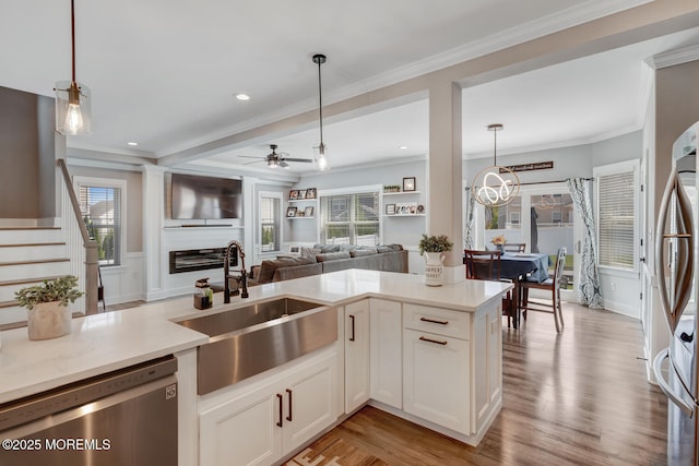 kitchen with a sink, ceiling fan with notable chandelier, stainless steel appliances, open floor plan, and pendant lighting