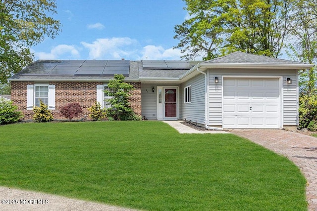 ranch-style house with an attached garage, driveway, solar panels, and a front yard