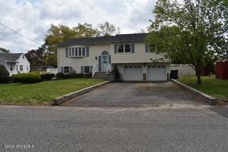 raised ranch with a front lawn, aphalt driveway, and a garage