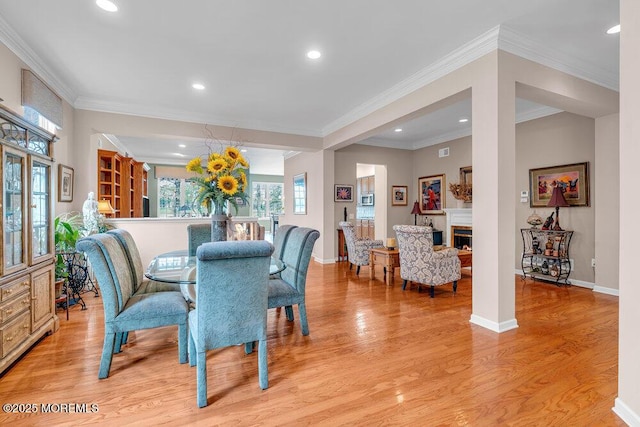 dining area featuring light wood-type flooring, a fireplace, recessed lighting, baseboards, and ornamental molding