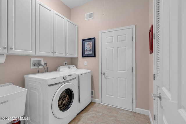 clothes washing area with washer and dryer, cabinet space, and baseboards