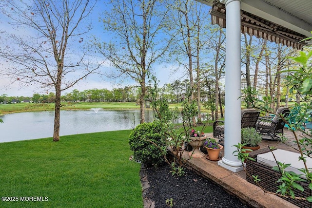 view of green lawn featuring a water view