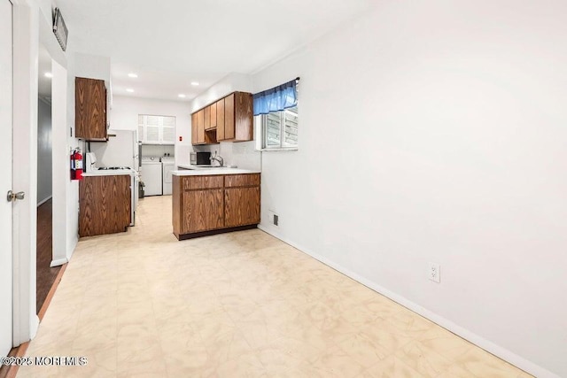 kitchen with light countertops, brown cabinetry, a healthy amount of sunlight, and light floors