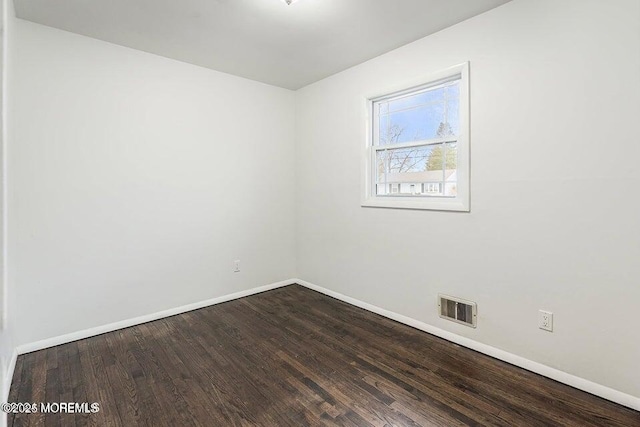 unfurnished room featuring visible vents, baseboards, and dark wood finished floors