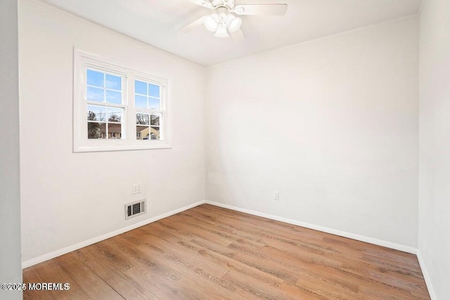 unfurnished room with baseboards, wood finished floors, and visible vents