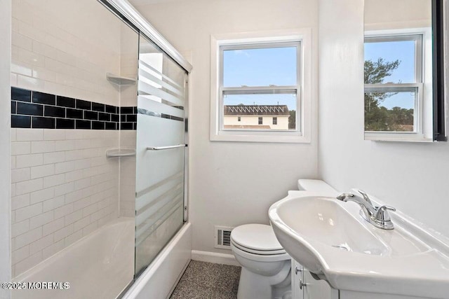 full bathroom with shower / bath combination with glass door, vanity, toilet, baseboards, and visible vents