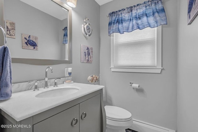half bath with toilet, baseboard heating, and vanity