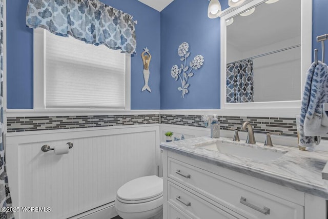 full bath featuring toilet, wainscoting, tasteful backsplash, and vanity