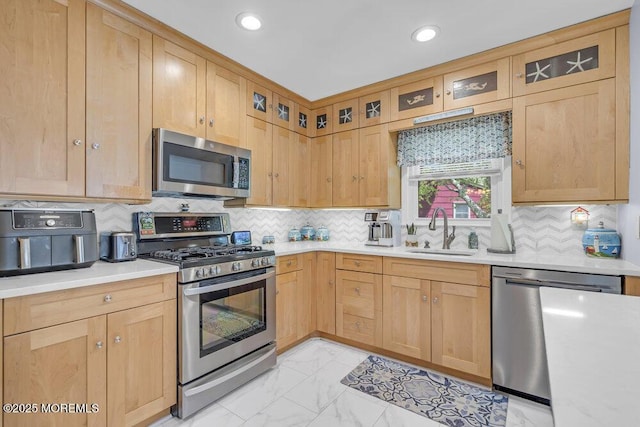 kitchen with backsplash, appliances with stainless steel finishes, a sink, light countertops, and marble finish floor