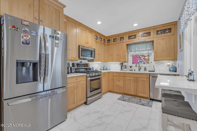 kitchen featuring appliances with stainless steel finishes, a sink, light countertops, marble finish floor, and glass insert cabinets