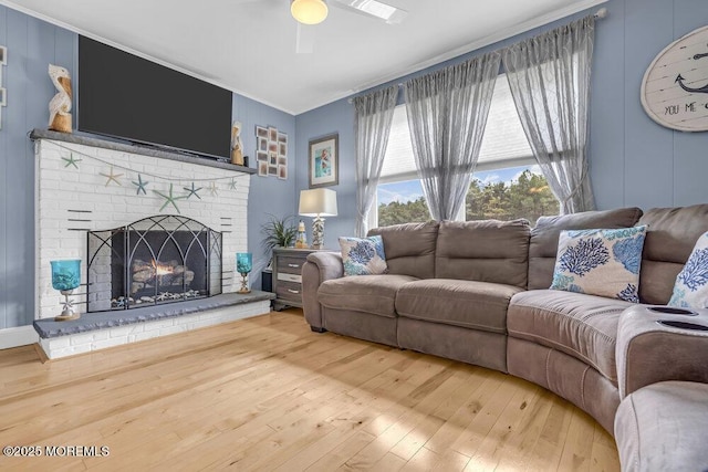 living room with crown molding, a brick fireplace, ceiling fan, and hardwood / wood-style floors