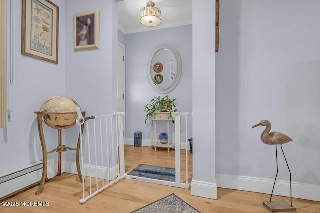 hallway featuring baseboards, ornamental molding, wood finished floors, and baseboard heating