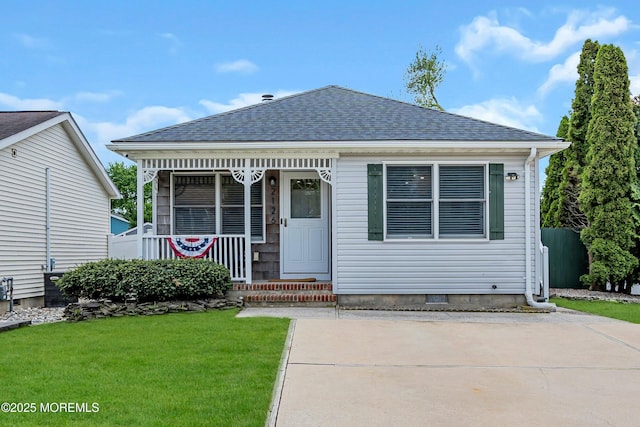 view of front facade featuring a front lawn, a porch, and roof with shingles