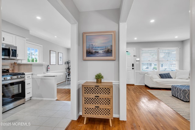 kitchen with stainless steel appliances, white cabinets, light wood-type flooring, light countertops, and recessed lighting