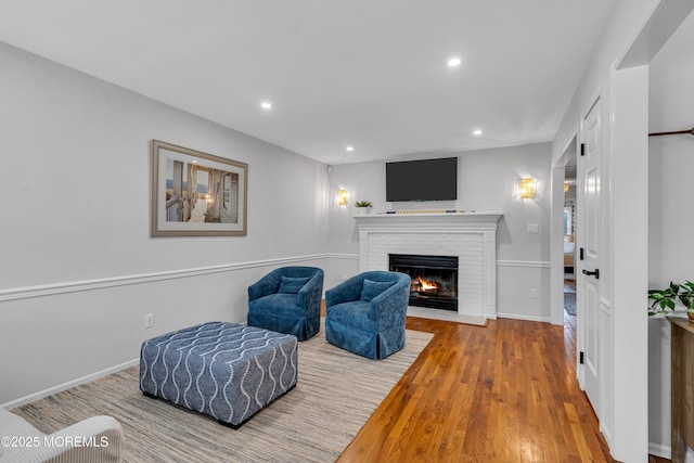 living area with a fireplace, recessed lighting, wood finished floors, and baseboards
