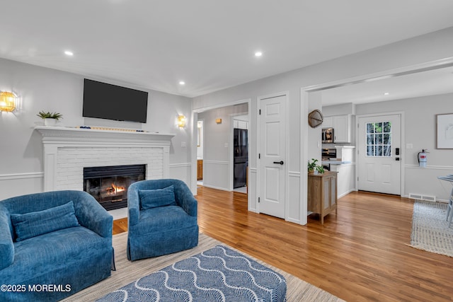 living room with a fireplace, light wood-type flooring, and recessed lighting