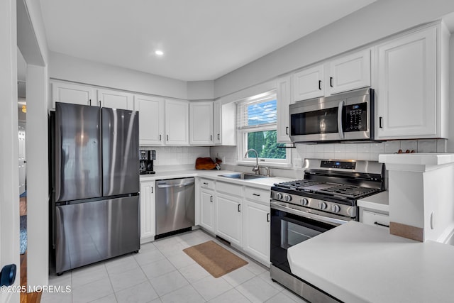 kitchen with appliances with stainless steel finishes, a sink, light countertops, white cabinetry, and recessed lighting