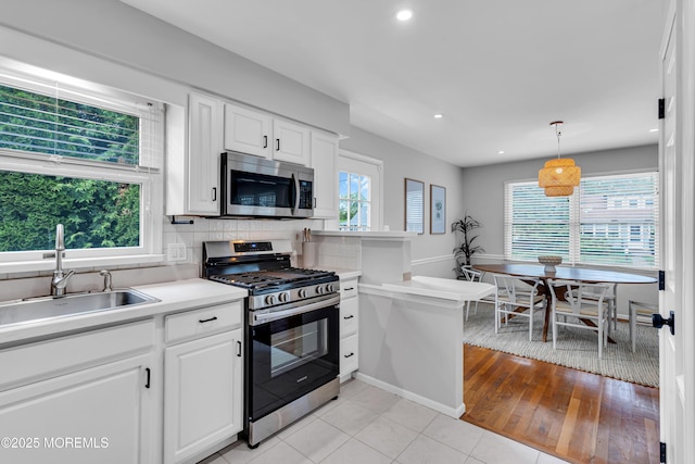 kitchen featuring appliances with stainless steel finishes, a sink, light countertops, white cabinetry, and recessed lighting