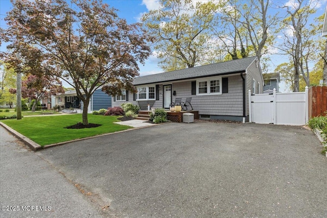 single story home featuring a shingled roof, a gate, fence, and a front yard